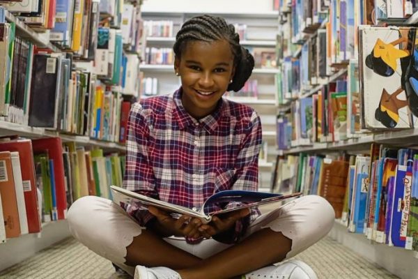 Marley Dias sitting in a library reading a book