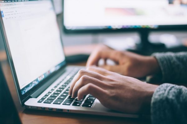 Close-up of a person writing on a laptop.