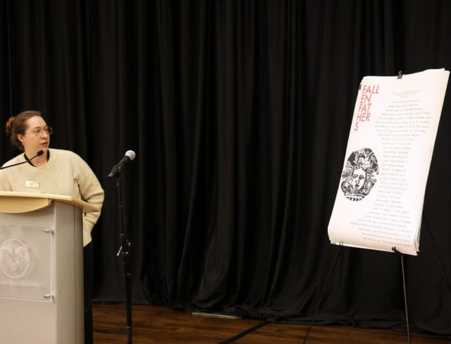 GradShow_web11 Bianca Glinskas at podium presenting beside poster titled "Fall Like Father" at Graduate Student Showcase, Nov. 19.