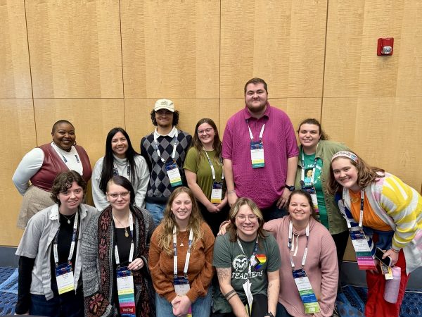 Large group photo of NCTE convention attendees in casual attire, standing and kneeling together.
