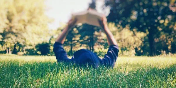 Person lying in grass reading