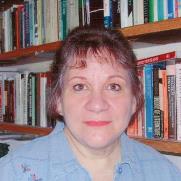 A photo of Marnie Leonard looking at the camera with a bookshelf in the background