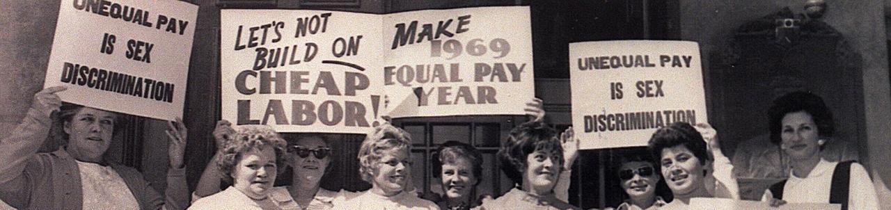 Women holding signs about equal work equal pay at one of the first Equal Pay Day rallies
