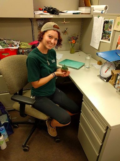 Kenna Castleberry sitting at a desk holding a plant