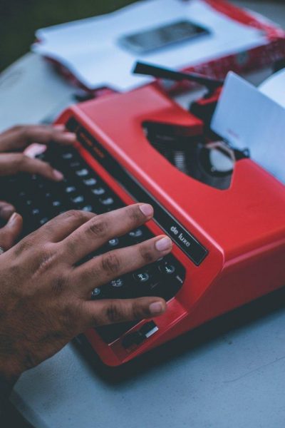 Hands typing on red typewriter