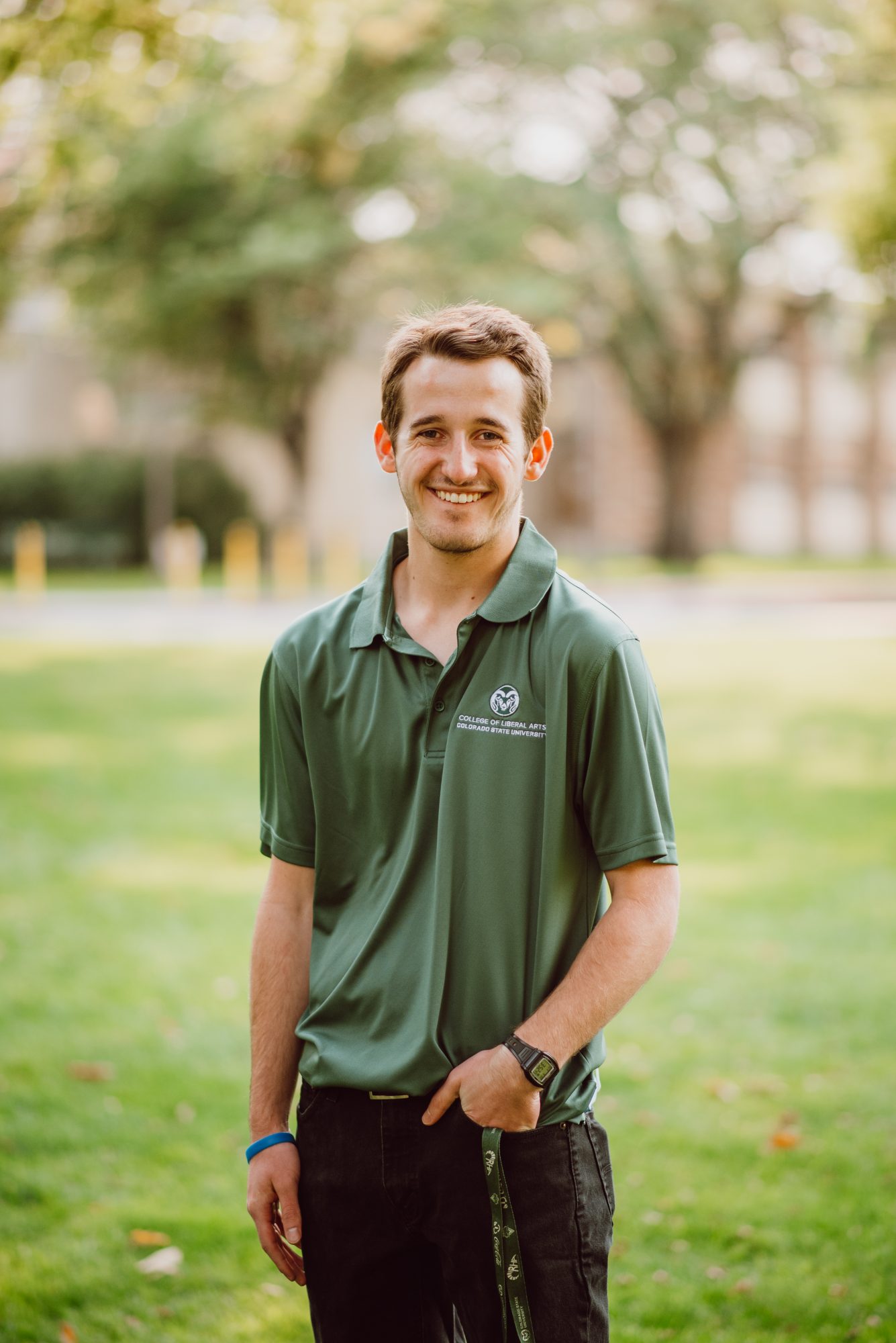 Portrait of Pete Wilson. A student with short brown hair stands on a green lawn wearing a green polo and black pants.