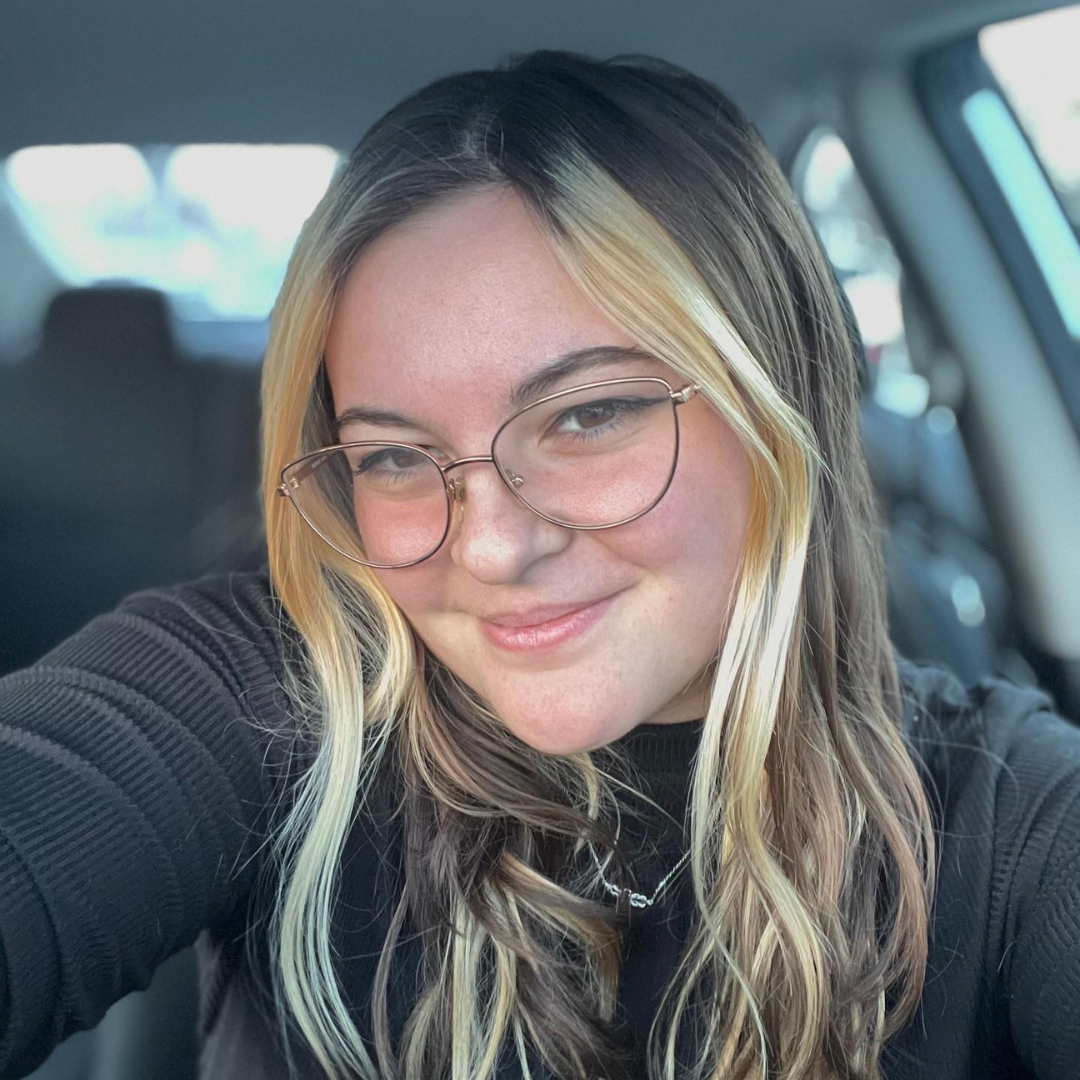 Portrait of Izzy Blosser. Student is wearing a black shirt and has long blonde hair and glasses.
